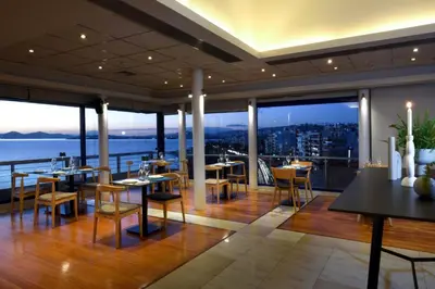 a restaurant with tables and chairs on a balcony at Poseidon Athens Hotel in Athens