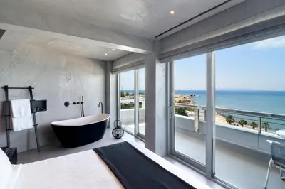 a bathroom with a tub and a view of the ocean at Poseidon Athens Hotel in Athens