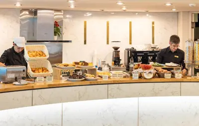 two chefs preparing food in a restaurant kitchen at Ilisia Hotel Athens in Athens