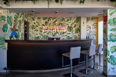 a bar with chairs against a wall with plants at Athens Way Pop Art Hotel in Athens
