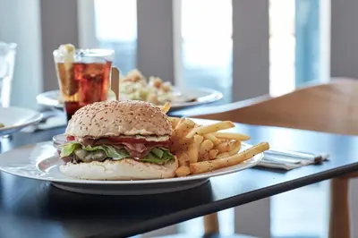 a sandwich and french fries on a table with a drink at Candia Hotel in Athens