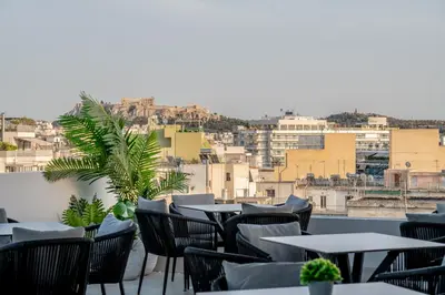 a balcony with tables and chairs and a city at Candia Hotel in Athens
