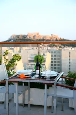 a table with a bottle of wine sitting on a balcony at Dorian Inn - Sure Hotel Collection by Best Western in Athens