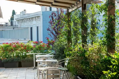 a patio with tables and chairs and flowers at Kimon Hotel Athens in Athens