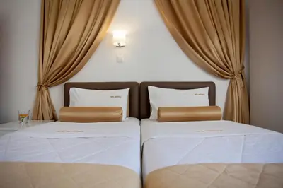 two beds in a room with curtains at Metropolis Hotel in Athens