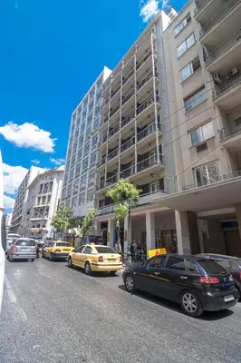 a street with cars parked in front of a building at Ares Athens Hotel in Athens