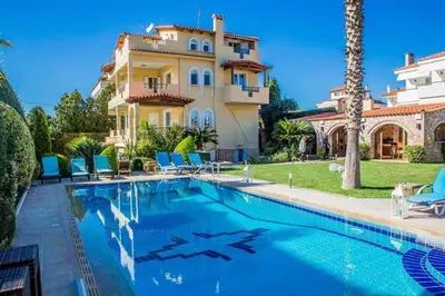 a villa with a swimming pool in front of a house at Lagonisi Villa VIP in Lagonissi