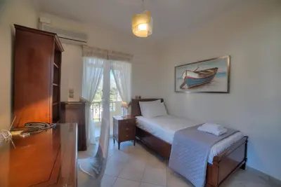 a bedroom with a bed and a dresser and a window at Lagonisi Villa VIP in Lagonissi