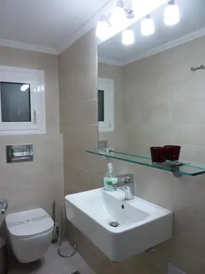 a bathroom with a sink and a toilet and a mirror at Architect Designer's Apartment in Kolonaki in Athens