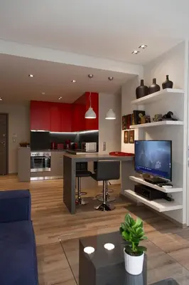 a living room with a kitchen with a desk and a tv at Luxury 2 bdrm apartment 10' minutes walk from the Acropolis in Athens