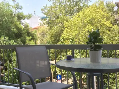 a table and chair on a balcony with a potted plant at Luxury 2 bdrm apartment 10' minutes walk from the Acropolis in Athens