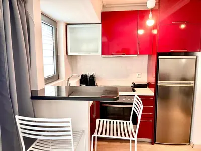 a small kitchen with red cabinets and white chairs at Elvita Apartments in Athens