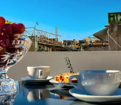 a table with two cups and a vase of fruit at Carolina Hotel since 1934 in Athens