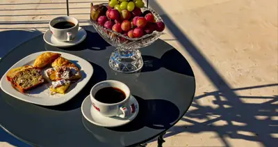a table with two cups of coffee and a bowl of fruit at Carolina Hotel since 1934 in Athens