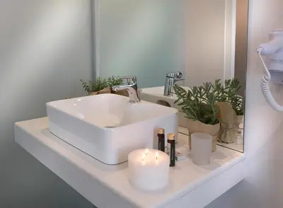 a bathroom sink with two candles and a mirror at Carolina Hotel since 1934 in Athens