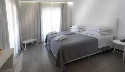 a white bedroom with two beds and a window at Carolina Hotel since 1934 in Athens