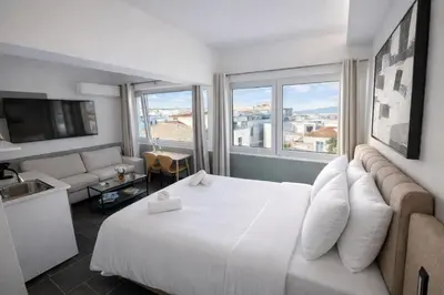 a hotel room with a large white bed and windows at Elite Ermou Suites in Athens