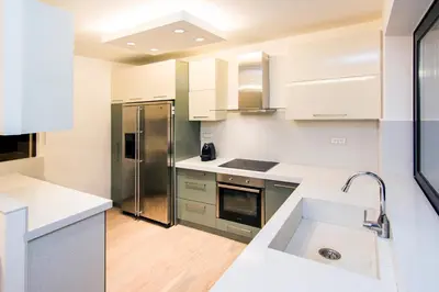 a kitchen with white cabinets and a stainless steel refrigerator at Hidden Sanctuary In Saronida in Anavissos