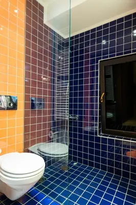 a blue tiled bathroom with a toilet and a shower at Hidden Sanctuary In Saronida in Anavissos