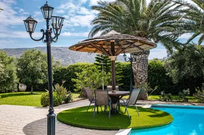 a table and chairs under an umbrella next to a pool at Villa Noaina in Lagonissi in Lagonissi