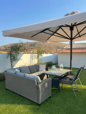 a couch and a table under a large umbrella at Villa Noaina in Lagonissi in Lagonissi