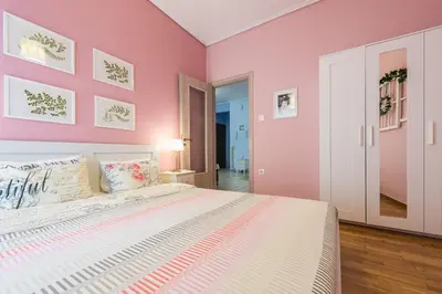 a bedroom with pink walls and a large bed at Zenios Hercules - Stylish apartment near Acropolis in Athens