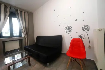 a living room with a black chair and dandelions on the wall at Gazi Boutique Apartment 2 in Athens