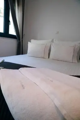 a bed with white sheets and pillows in a room at Gazi Boutique Apartment 2 in Athens