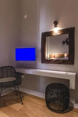a living room with a tv and a chair and a mirror at Acropolis Luxury Apartments in Athens