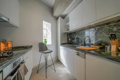 a kitchen with white cabinets and a chair in it at ApArt Suite in Athens
