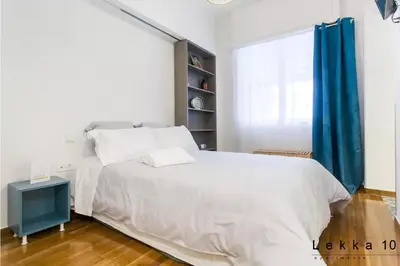 a bedroom with a white bed and blue curtains at Lekka 10 Apartments in Athens