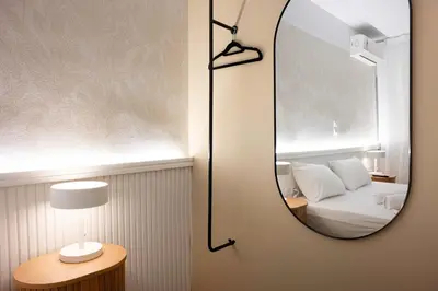 a mirror on a wall next to a bed at LUX Hotel in Piraeus