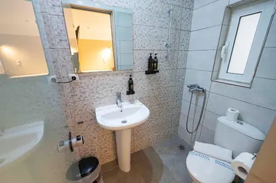 a bathroom with a sink and a toilet and a mirror at LUX Hotel in Piraeus