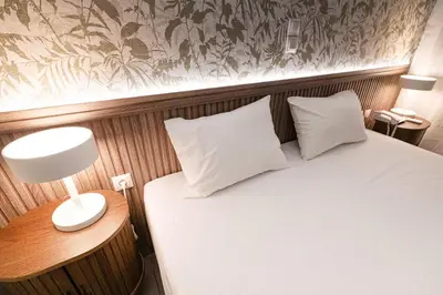 a bed with two pillows and a lamp on a table at LUX Hotel in Piraeus