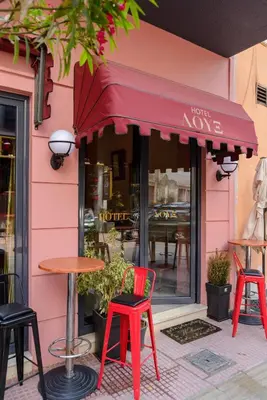 a pink building with two red chairs and a table at LUX Hotel in Piraeus