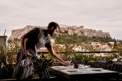 a man standing next to a table with wine glasses at The Zillers Boutique Hotel in Athens