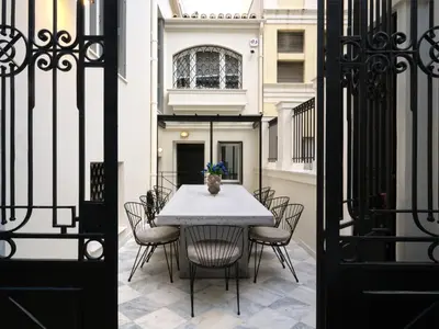 a table and chairs in a courtyard with a building at The White House in Plaka by JJ Hospitality in Athens