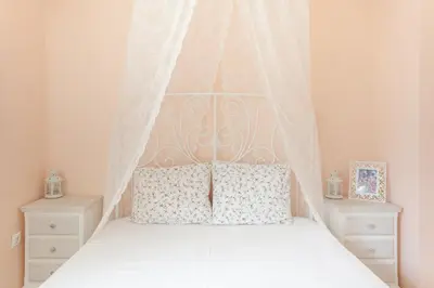 a white bed with a canopy and two night stands at Markella's House in Vravrona