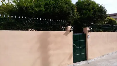 a fence with a green gate with trees in the background at Markella's House in Vravrona