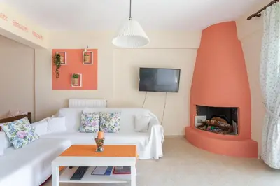 a living room with a white couch and a fireplace at Markella's House in Vravrona