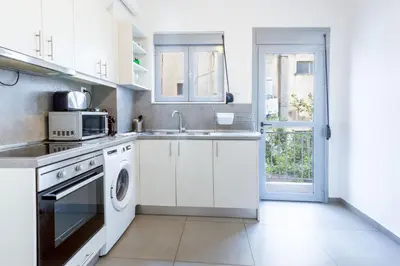 a white kitchen with a sink and a microwave at Renovated 4 Bdr House near Acropolis - New Beds, Terrace & Green Yard in Athens