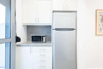 a white kitchen with a refrigerator and a microwave at Renovated 4 Bdr House near Acropolis - New Beds, Terrace & Green Yard in Athens