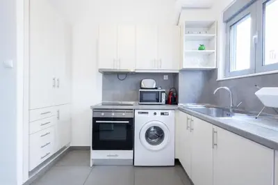 a white kitchen with a washing machine and a sink at Renovated 4 Bdr House near Acropolis - New Beds, Terrace & Green Yard in Athens