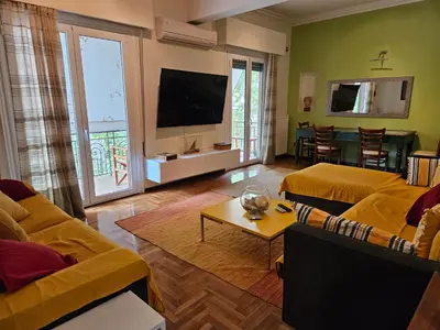 a living room with yellow furniture and a flat screen tv at 3 bedder condo in Ilisia, Megaro Mousikis in Athens