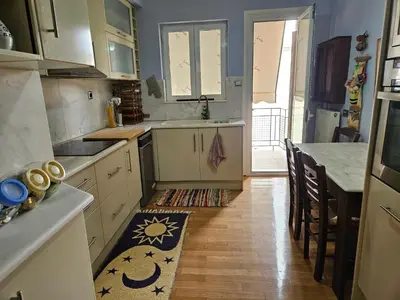 a kitchen with white cabinets and a wooden floor at 3 bedder condo in Ilisia, Megaro Mousikis in Athens