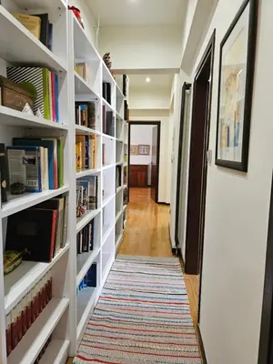 a hallway with white book shelves filled with books at 3 bedder condo in Ilisia, Megaro Mousikis in Athens