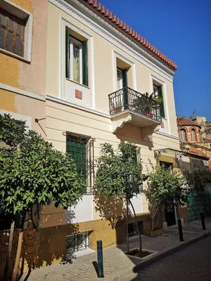 a building with a balcony and trees in front of it at Psyri Neoclassical House Yard Free Parking in Athens
