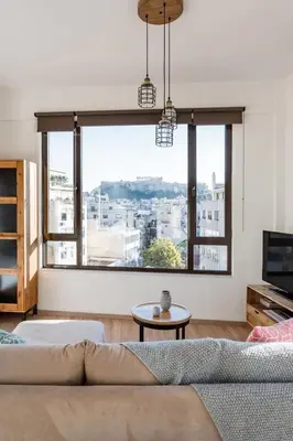 a living room with a couch and a large window at Explore Nightlife Near an Apartment With an Acropolis View in Athens