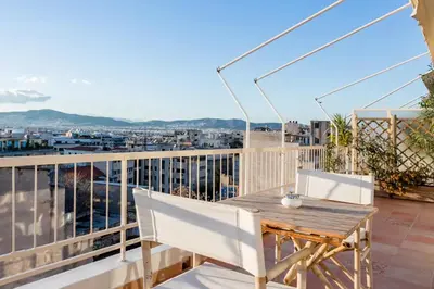 a balcony with a wooden table and white chairs at Explore Nightlife Near an Apartment With an Acropolis View in Athens