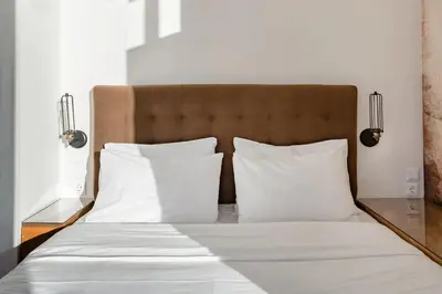 a bed with white sheets and pillows on it at Explore Nightlife Near an Apartment With an Acropolis View in Athens